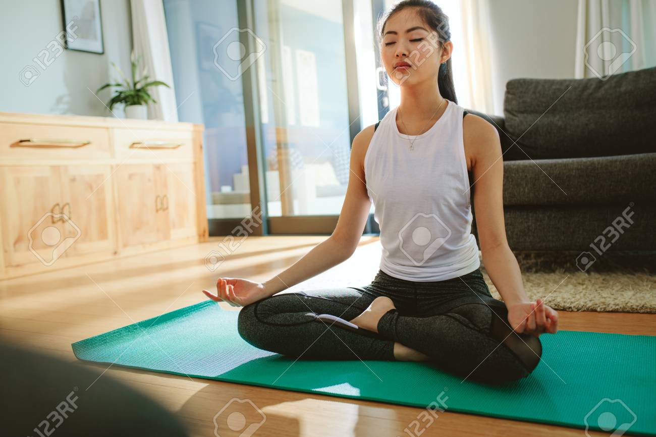 Fit young female meditating in lotus pose at home. Beautiful woman doing yoga exercise indoors. - 118800838 Fit young female meditating in lotus pose at home. Beautiful woman doing yoga exercise indoors. - 118800838