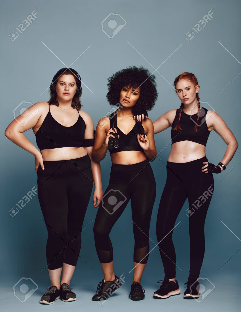 Grupo De Mujeres En Ropa Deportiva De Pie Juntas Fondo Gris. Mujeres De Diferente Raza, Tipo De Figura Y Tamaño En Ropa De Fitness. Fotos, Retratos, Imágenes Y Fotografía