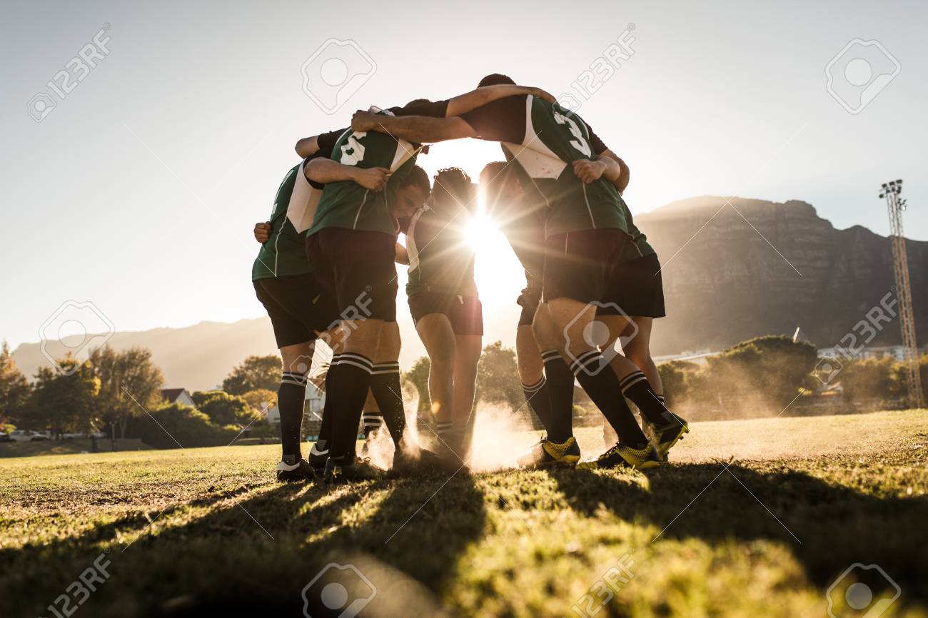 Rugby team standing in a huddle and rubbing their feet on ground. Rugby team celebrating victory. - 120521746 Rugby team standing in a huddle and rubbing their feet on ground. Rugby team celebrating victory. - 120521746