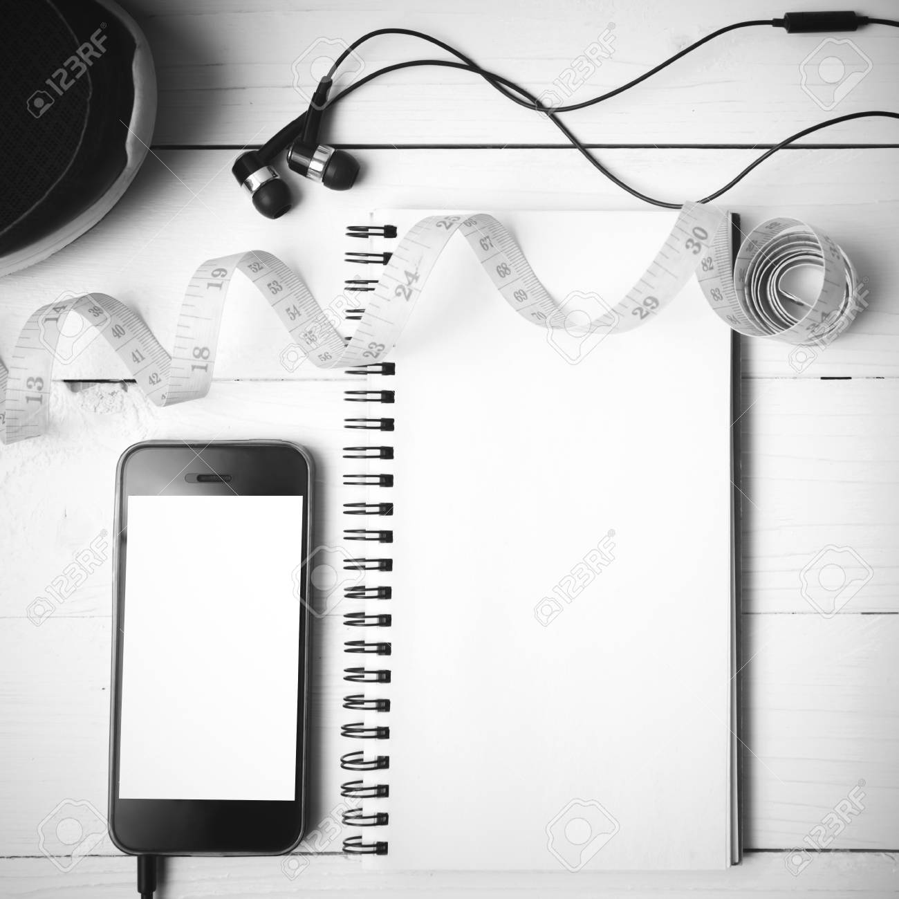 running shoes measuring tape notebook and phone on white wood and phone
