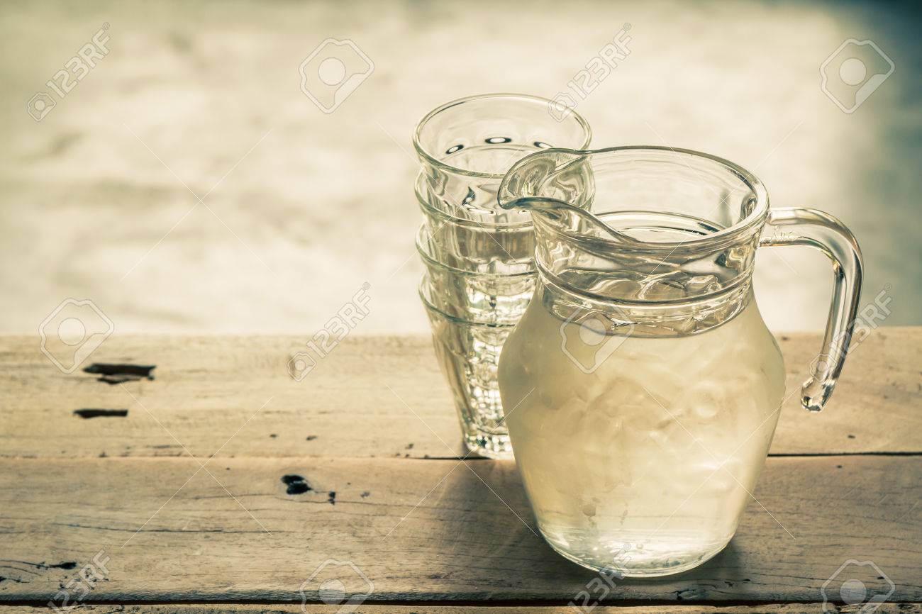 Immagini Stock Brocca Bicchiere D'acqua E Vetro Su Sfondo Bicchiere di vetro e la caraffa con acqua su un tavolo