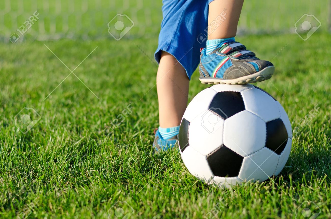 Little boy in shorts and trainers with his foot resting on top of a soccer ball on green grass with copyspace - 15887740 Little boy in shorts and trainers with his foot resting on top of a soccer ball on green grass with copyspace - 15887740