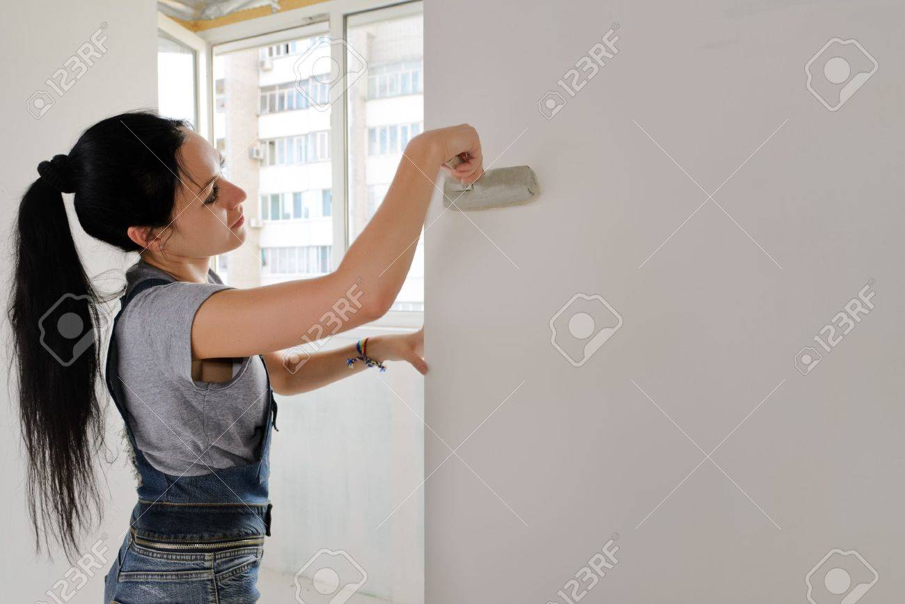 Woman painting an apartment wall finishing off the redecorating with a paintbrush - 20691930 Woman painting an apartment wall finishing off the redecorating with a paintbrush - 20691930