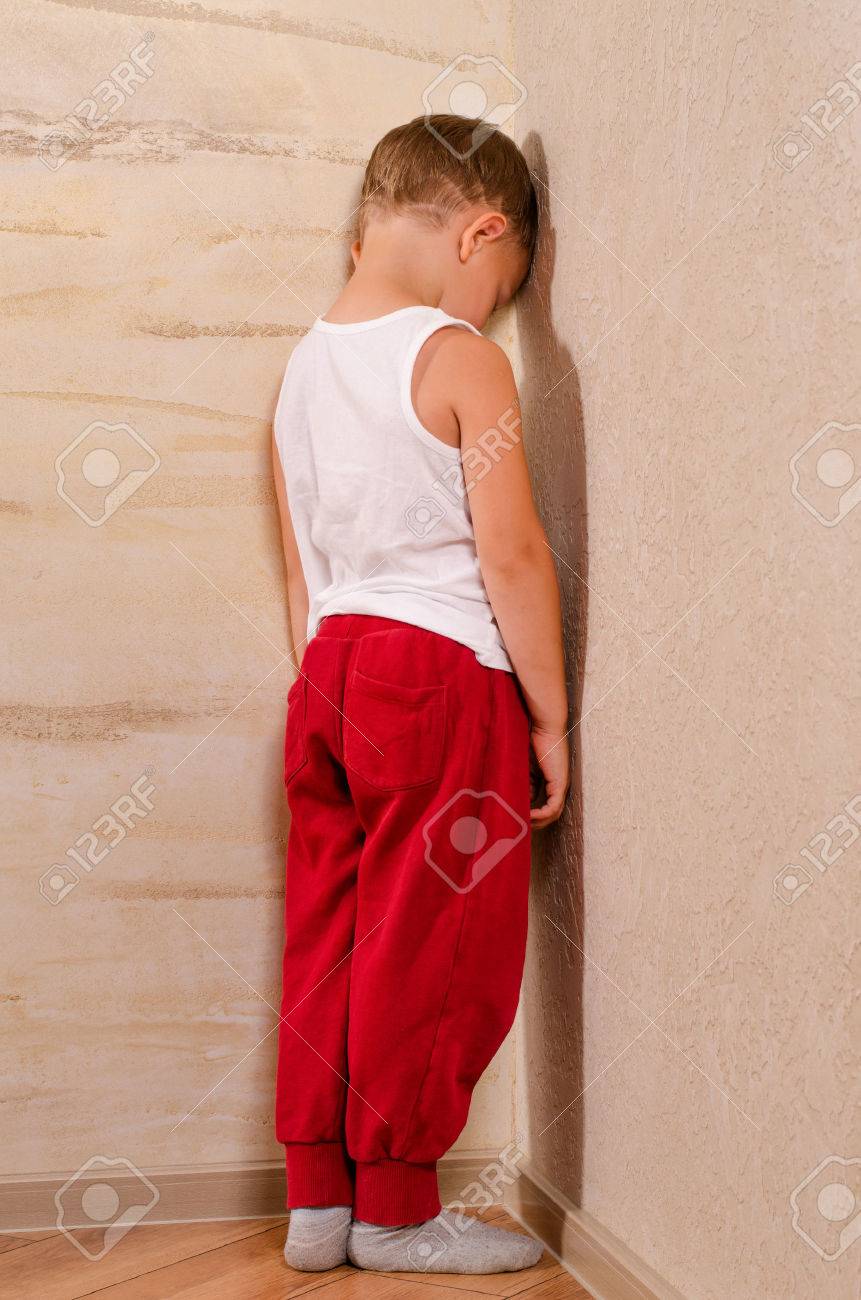 Little boy standing in a corner sulking turning to watch behind him with an angry morose expression, black and white portrait - 31182476 Little boy standing in a corner sulking turning to watch behind him with an angry morose expression, black and white portrait - 31182476