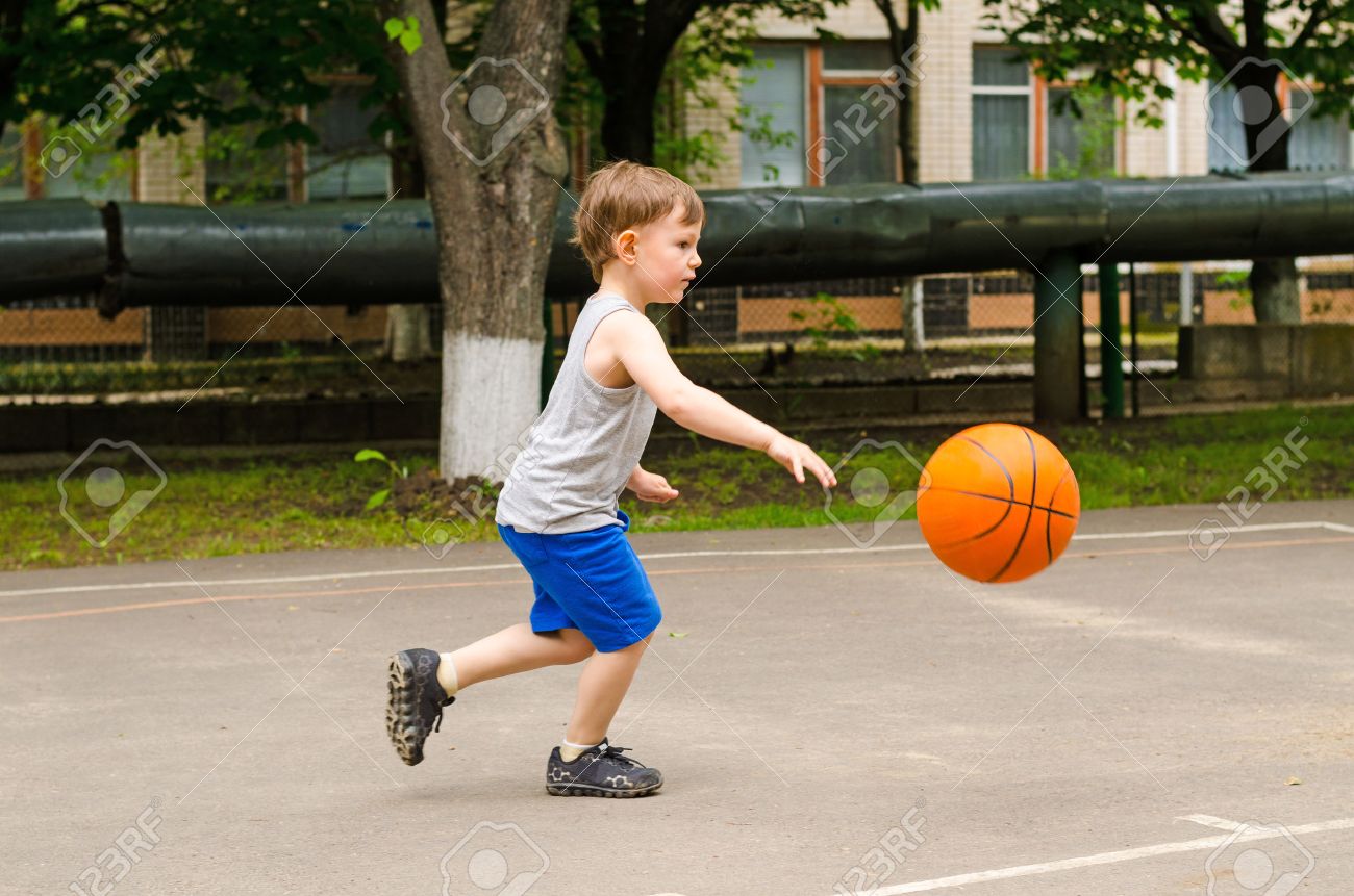 Little boy playing basketball running along the court in his sports wear bouncing the ball, side view outdoors - 34203229 Little boy playing basketball running along the court in his sports wear bouncing the ball, side view outdoors - 34203229