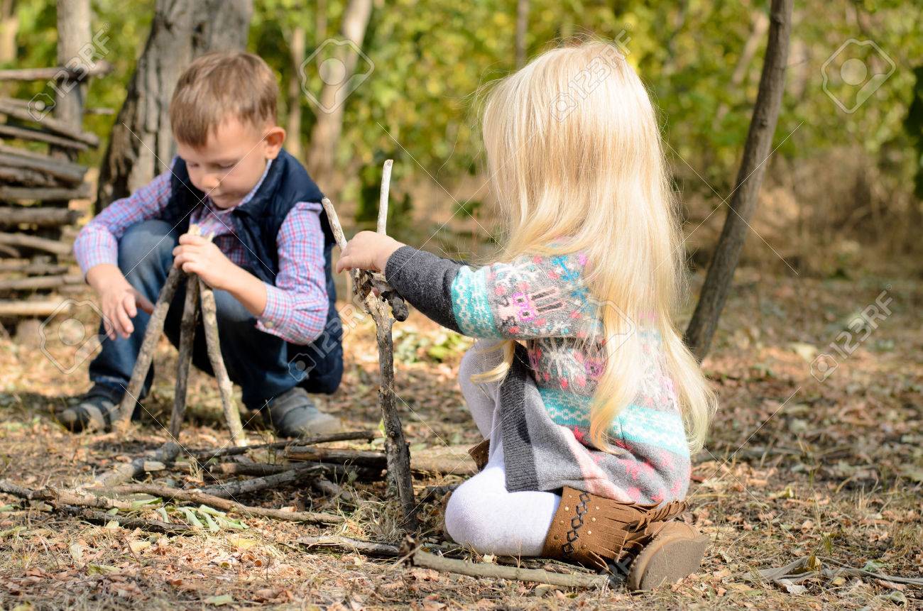Stylish little boy and girl playing in woodland with sticks happily crouching together on the ground building different structures - 36616870 Stylish little boy and girl playing in woodland with sticks happily crouching together on the ground building different structures - 36616870