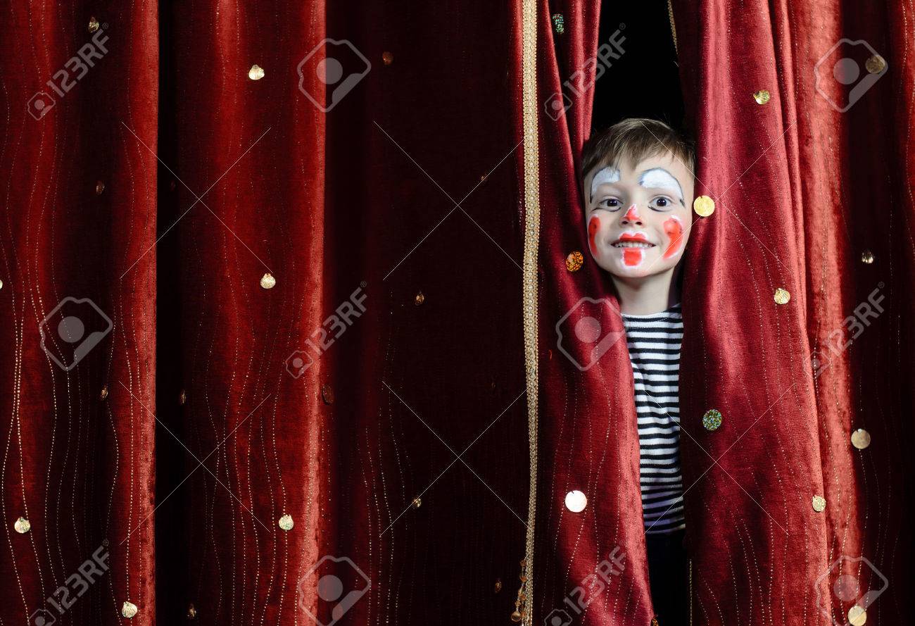 Young Boy Wearing Clown Make Up Peering Out Through Opening in Red Stage Curtains - 39420029 Young Boy Wearing Clown Make Up Peering Out Through Opening in Red Stage Curtains - 39420029