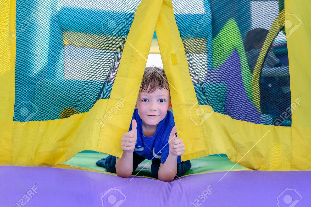 Single cute little curious boy with sweaty face looking from entrance of bouncy house - 56119450 Single cute little curious boy with sweaty face looking from entrance of bouncy house - 56119450