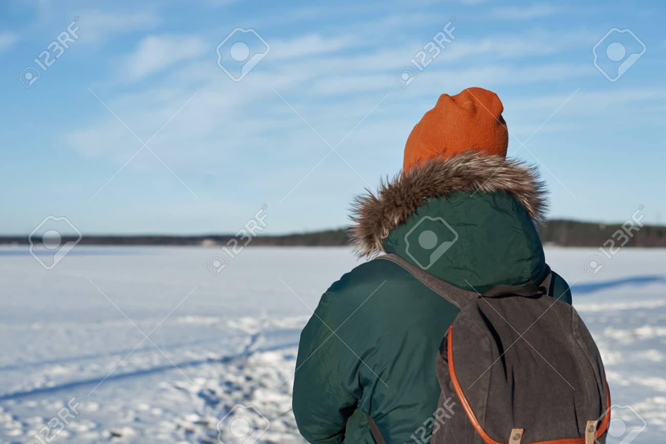 背面のバックパックと緑の冬ジャケットと赤い帽子のバックパッカー男の図 Travaler 商品を広告に空きが 青い空と白い光雲晴れた日の無料ホリゾント の写真素材 画像素材 Image
