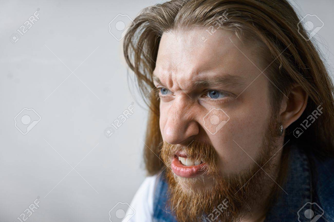 濃いひげと長い髪型顔をしかめ 彼の目は怒りと怒りに満ちて 歯を