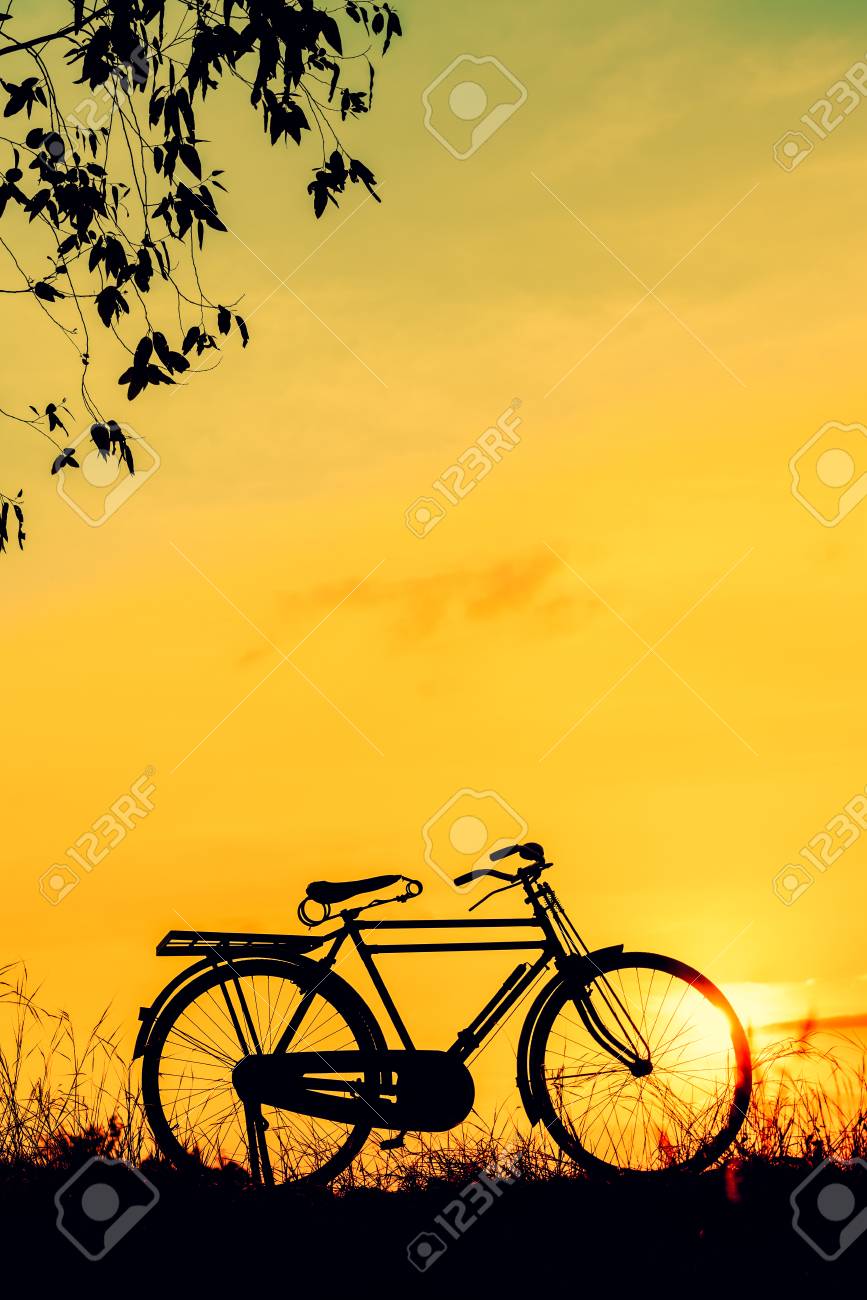 ヴィンテージトーンスタイルで夕日にシルエット自転車と美しい風景画像