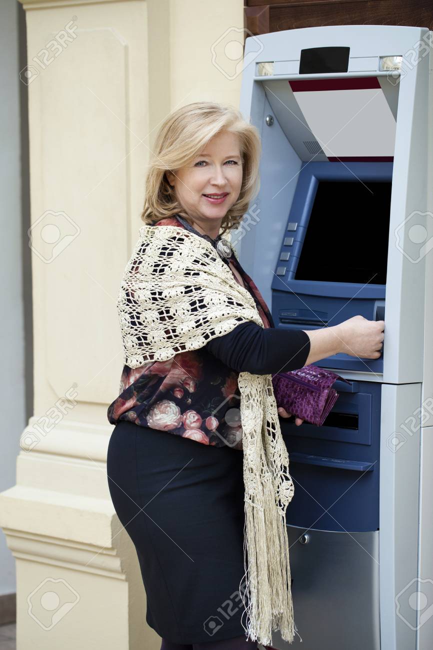 金髪熟女は店で自動預け払い機の近くに手でクレジット カード の写真素材 画像素材 Image