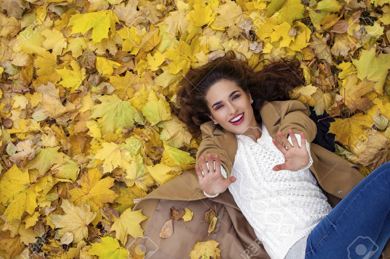 Young beautiful girl in blue jeans lying on yellow leaves, view from above, in the autumn park - 41188589 Young beautiful girl in blue jeans lying on yellow leaves, view from above, in the autumn park - 41188589
