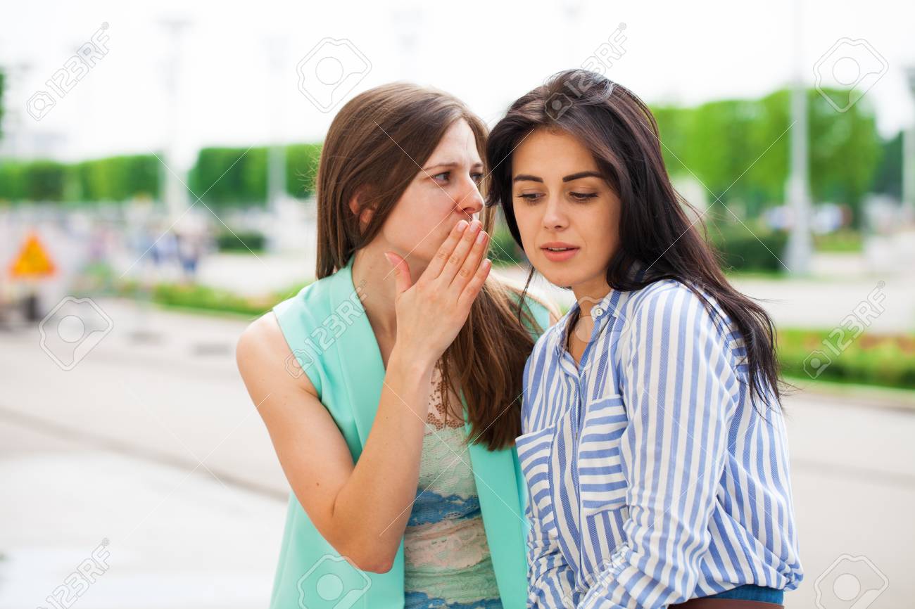 Two Young Women Talking To Each Other. Girl Friends Having A Chat 