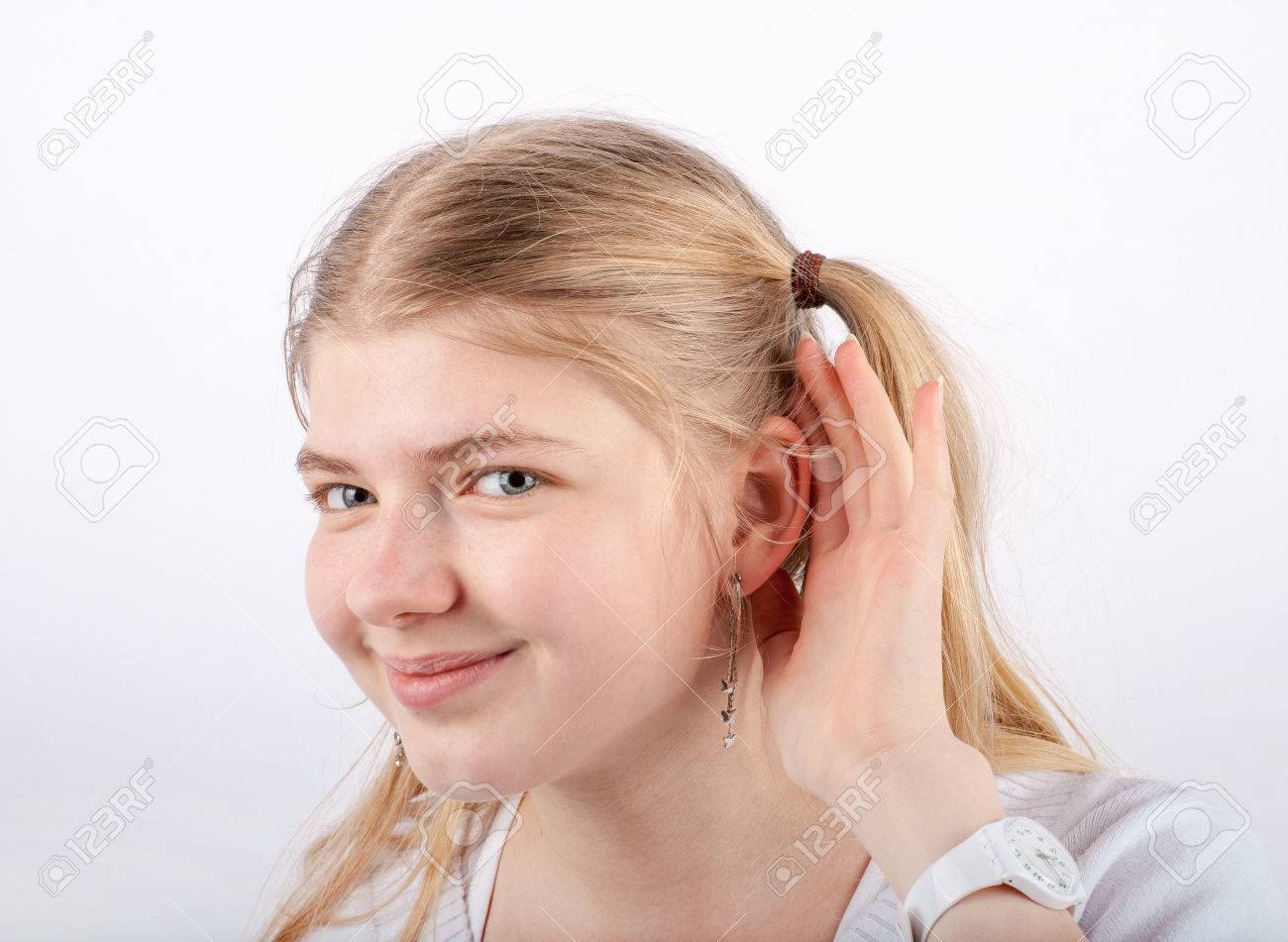 美しいブロンドの女の子は に手を彼女の耳の後ろをすくうと 笑みを浮かべて彼女を聞くことができません の写真素材 画像素材 Image