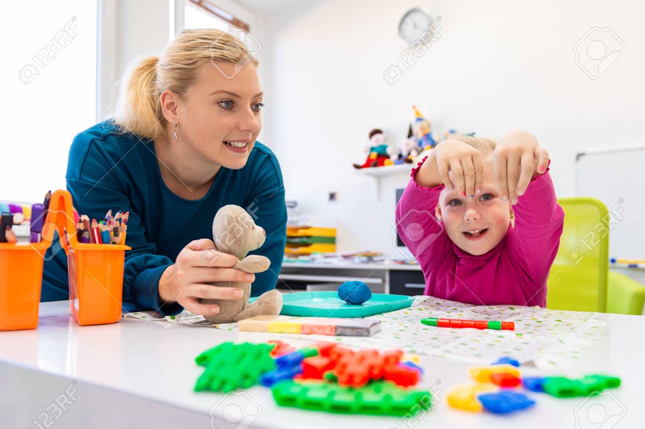 Toddler girl in child occupational therapy session doing sensory playful exercises with her therapist. - 117932507 Toddler girl in child occupational therapy session doing sensory playful exercises with her therapist. - 117932507