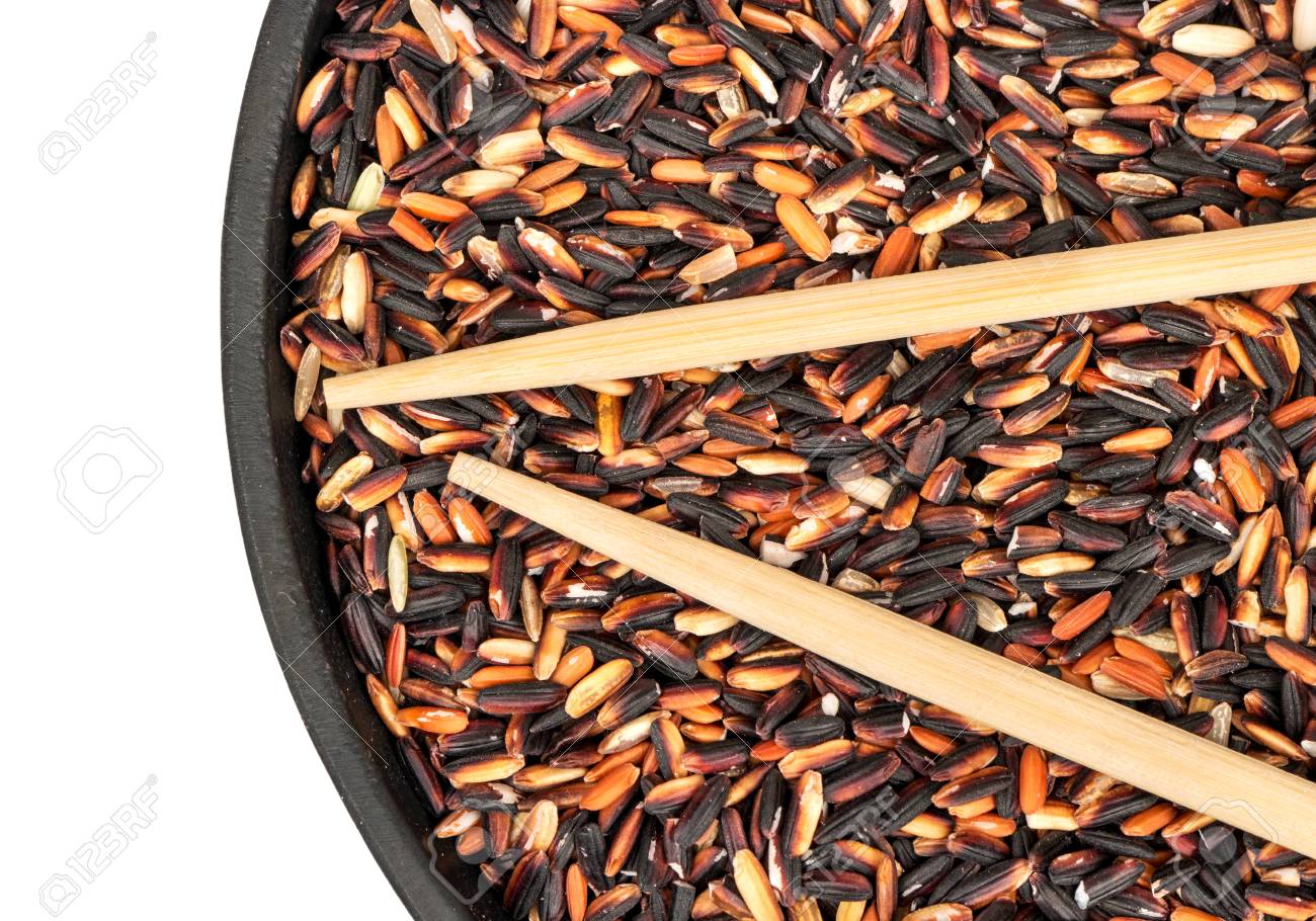 raw wild rice in a pan with chopsticks close up top view