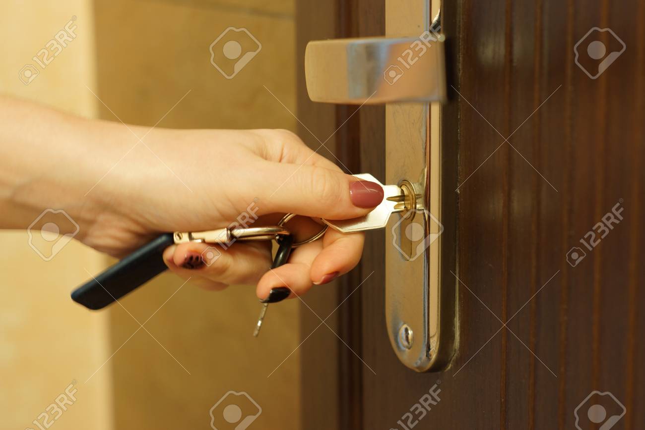 The woman turns the key in the lock on the outside door open - 66474043 The woman turns the key in the lock on the outside door open - 66474043