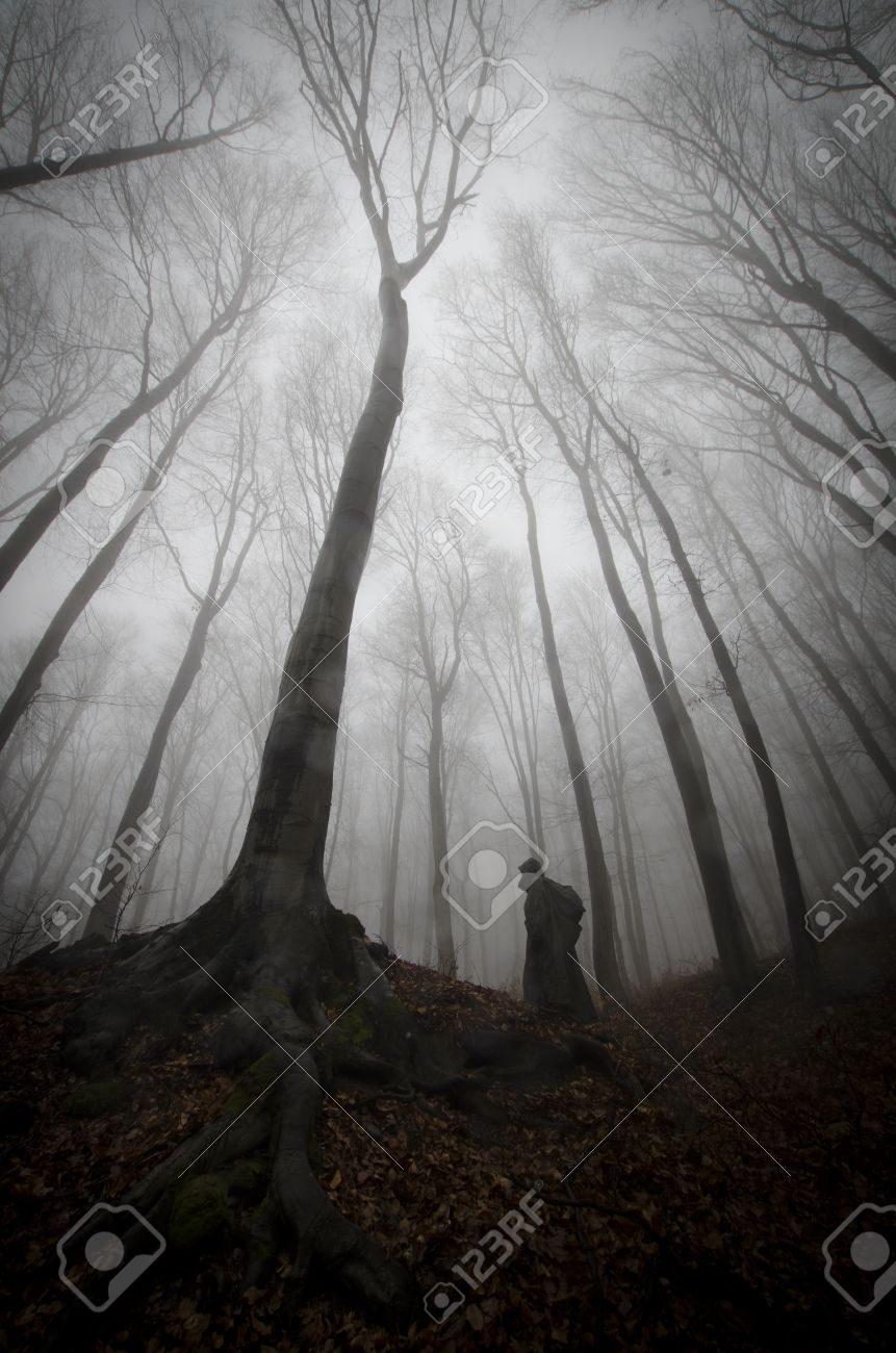vertical photo of scary man ghost near tree with big roots in vertical tree