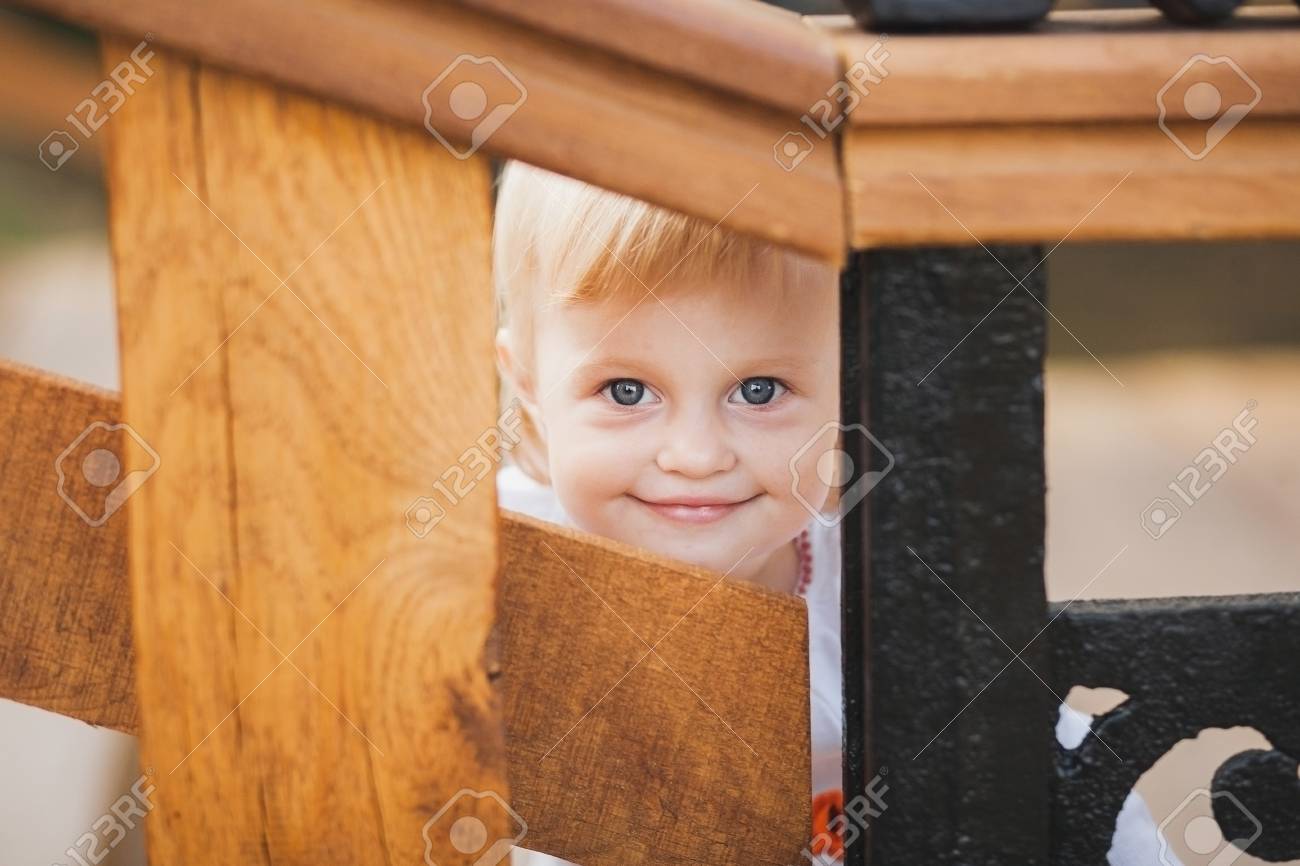 1 year old little caucasian girl palaing hide and seek game outdoors