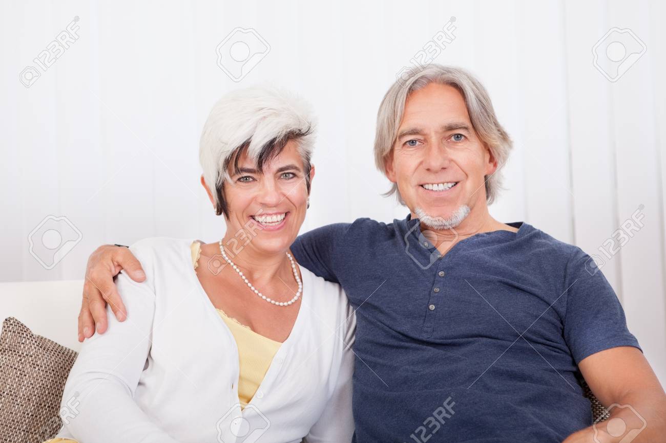 幸せな活力と老後の楽しみと晴れやかな近い抱擁で座っている老夫婦の笑顔 の写真素材 画像素材 Image