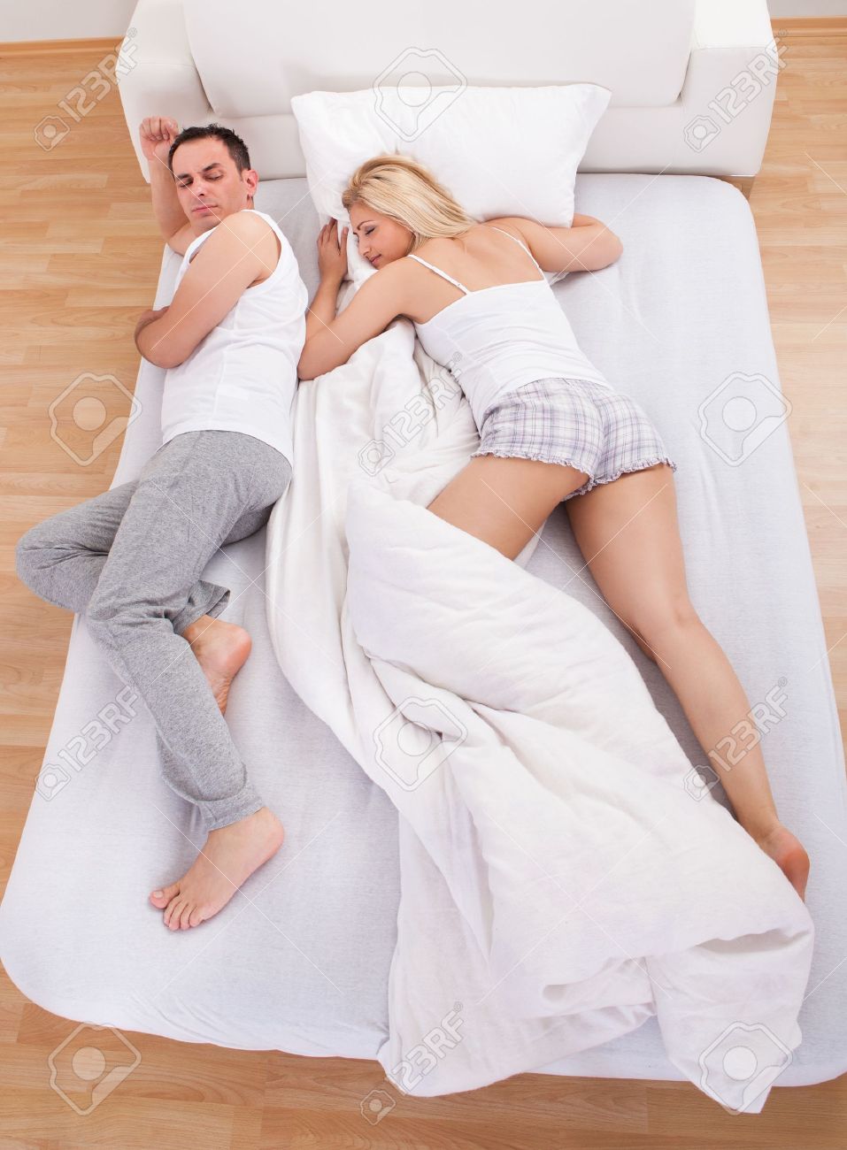 Uncomfortable Husband Sleeping With Wife On Bed