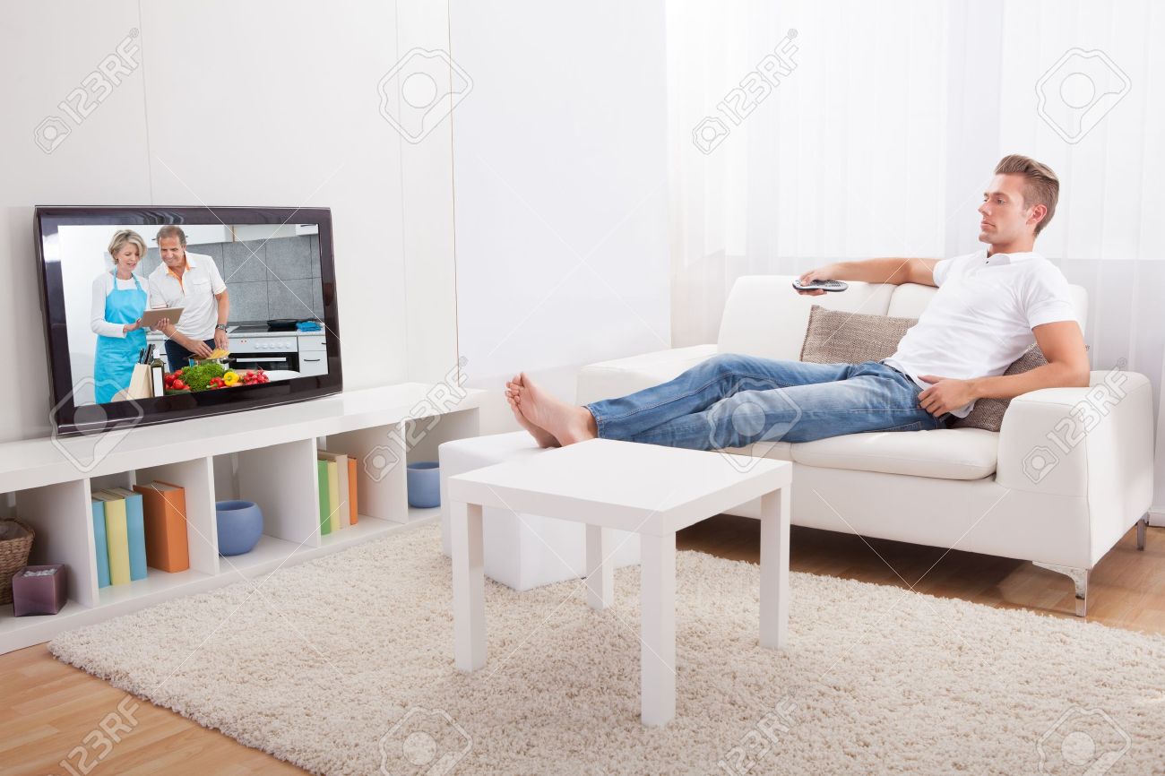 Young Man Sitting On Couch And Watching Movie At Home - 21668767 Young Man Sitting On Couch And Watching Movie At Home - 21668767