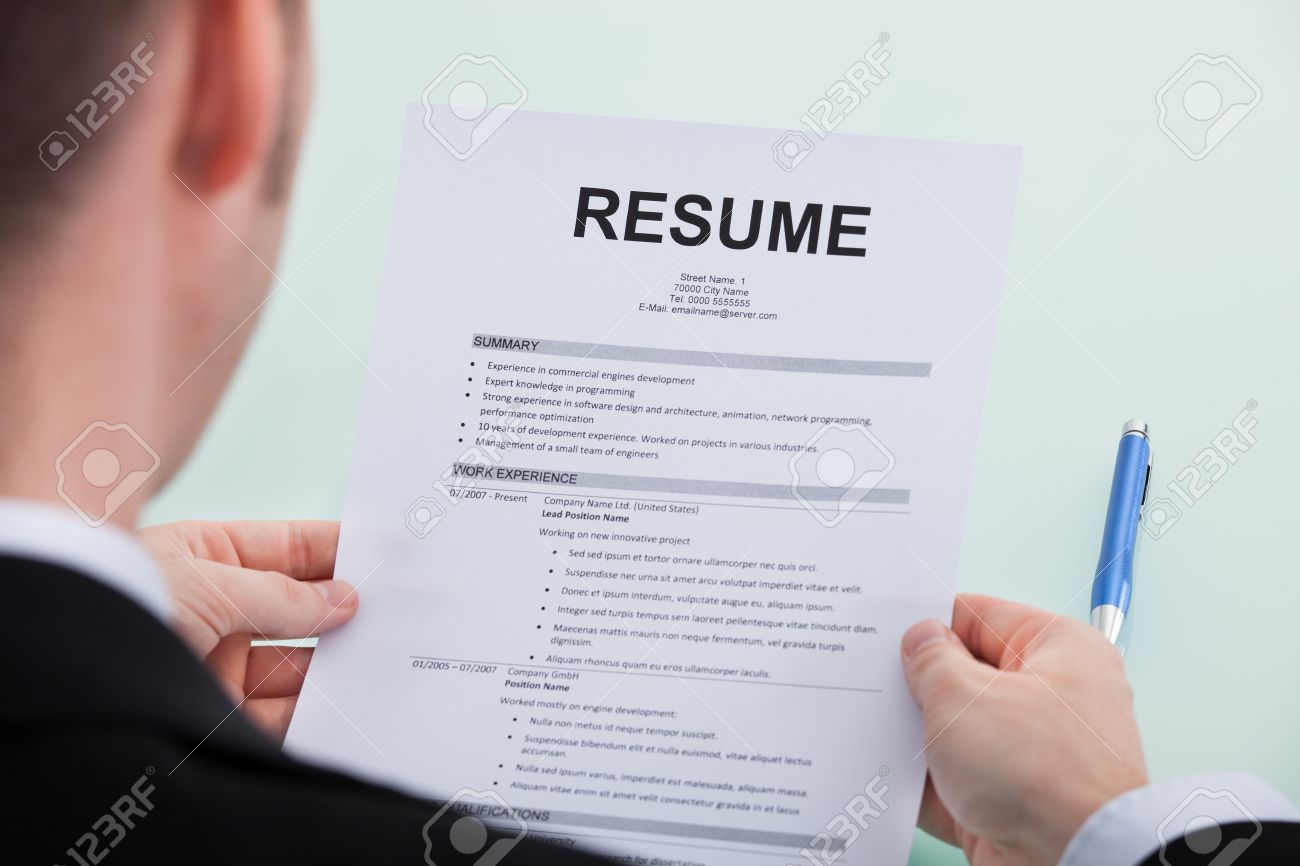cropped image of businessman reading resume at office desk stock