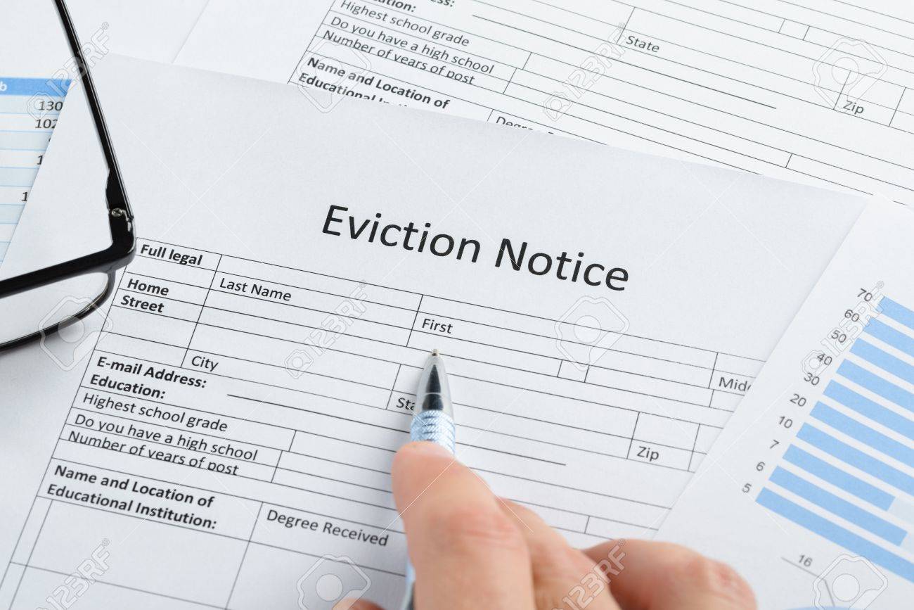 close up of hand with pen and eyeglasses over eviction notice