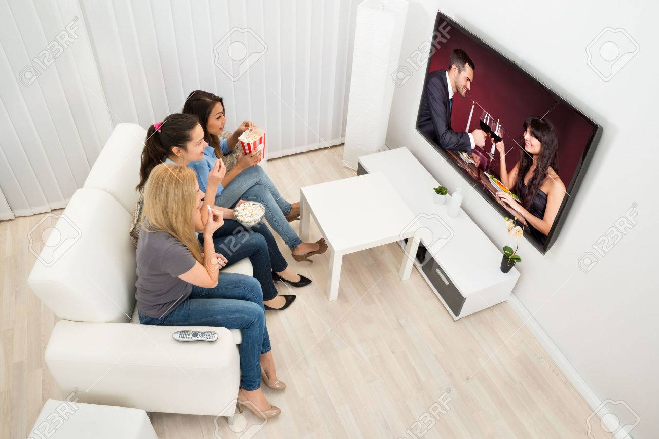 Multiethnic Young Women Sitting On Couch Watching Movie At Home - 36498085 Multiethnic Young Women Sitting On Couch Watching Movie At Home - 36498085