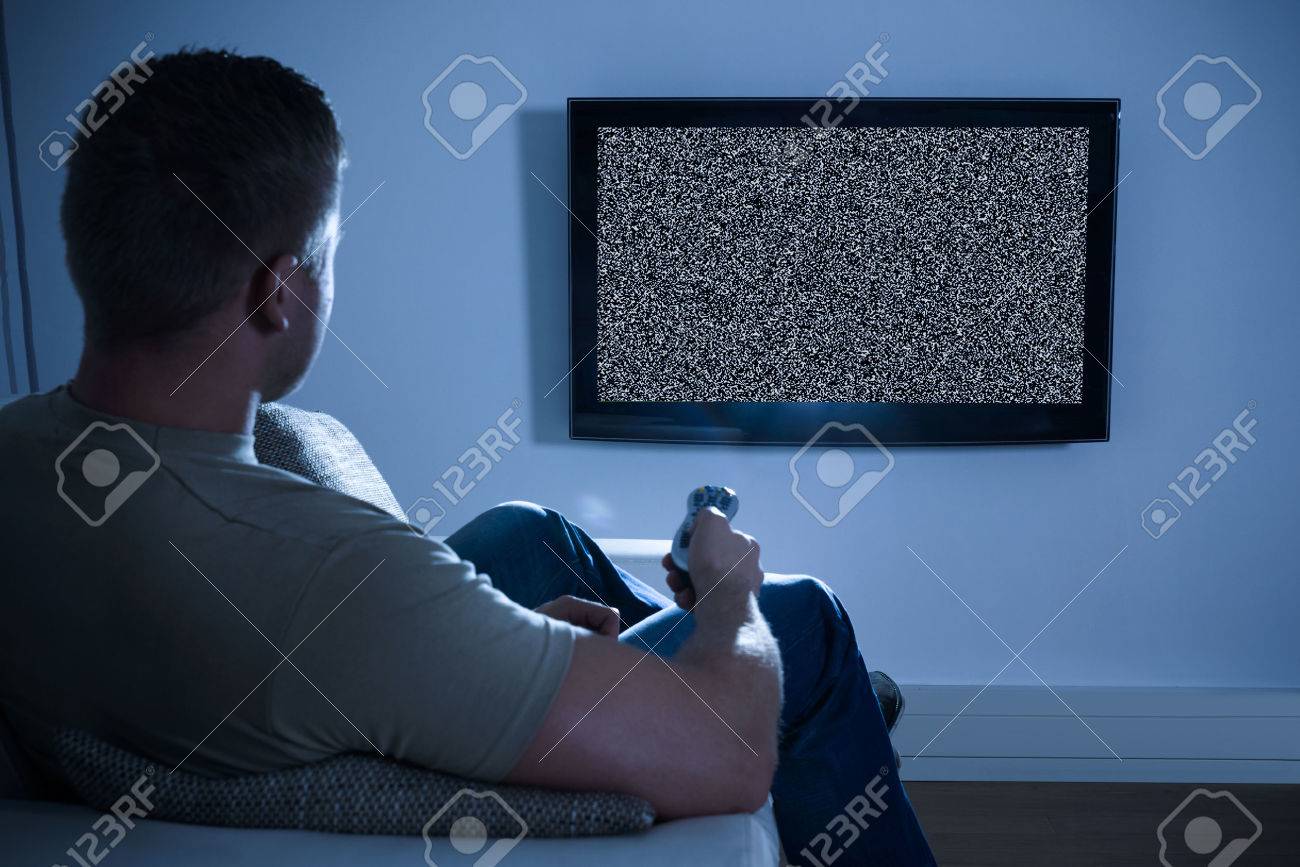 Man Sitting On Sofa In Front Of Television With No Signal - 39430080 Man Sitting On Sofa In Front Of Television With No Signal - 39430080