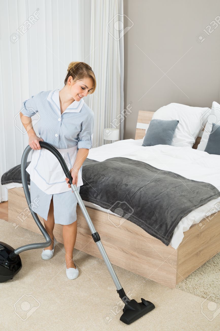 happy female housekeeper cleaning floor with vacuum cleaner in housekeeper pictures