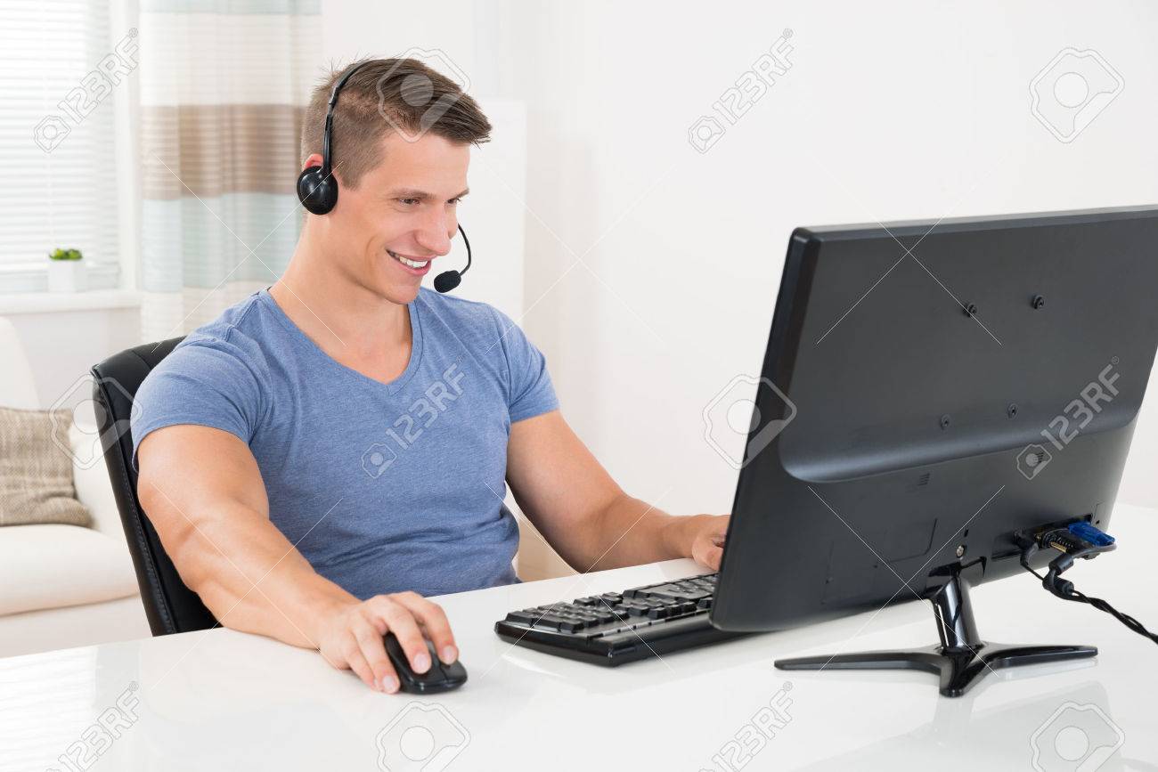 Happy Man Using Desktop Computer And Headset At Home Stock Photo, Picture  and Royalty Free Image. Image 45165850.