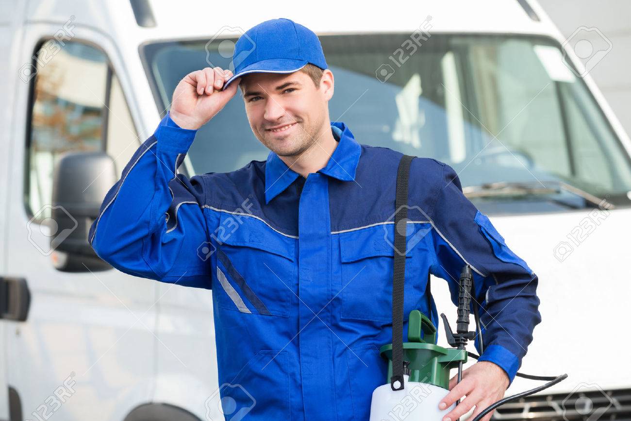 Portrait of confident pest control worker wearing cap against truck - 50278198 Portrait of confident pest control worker wearing cap against truck - 50278198