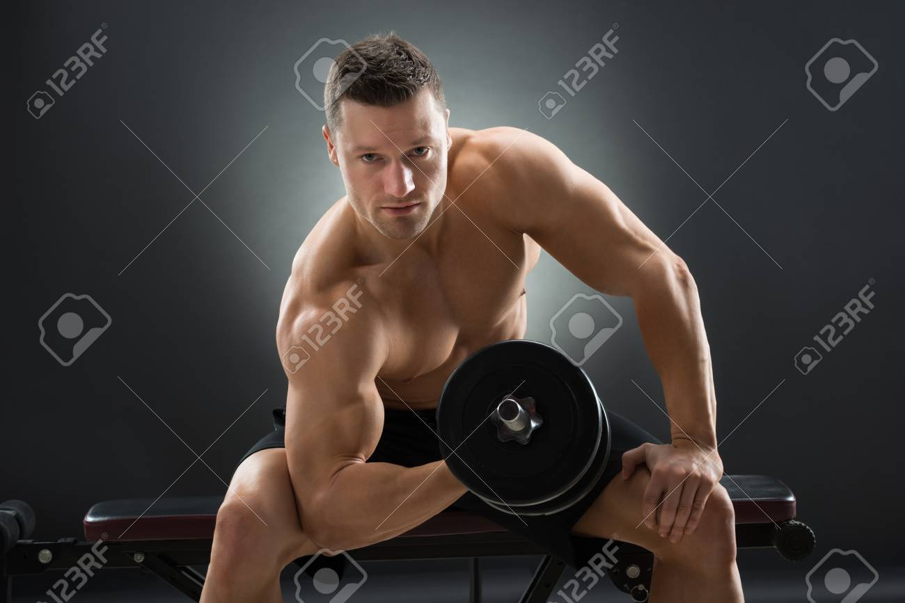 黒の背景に椅子に座りながらダンベル運動筋肉の男 の写真素材 画像素材 Image