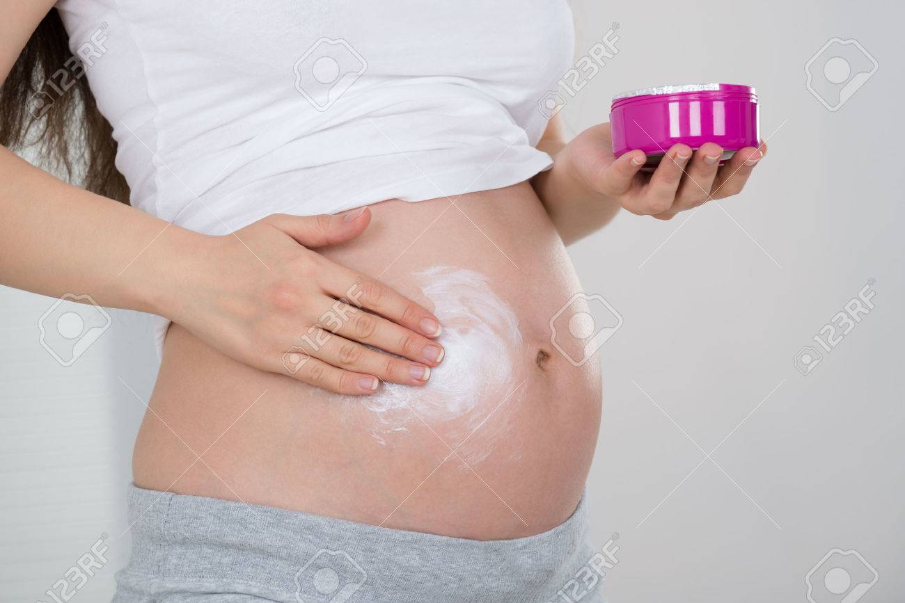 彼女のお腹にクリームを適用する妊娠中の女性のクローズ アップ の写真素材 画像素材 Image