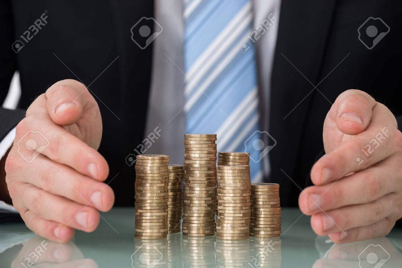 Close-up Of Businessperson Saving Pile Of Coins - 52952376 Close-up Of Businessperson Saving Pile Of Coins - 52952376