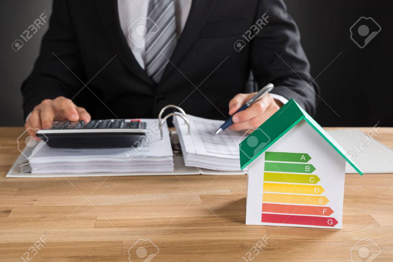 Businessman Calculating Financial Data With House Model Showing Energy Efficiency Rate On Desk - 55430015 Businessman Calculating Financial Data With House Model Showing Energy Efficiency Rate On Desk - 55430015