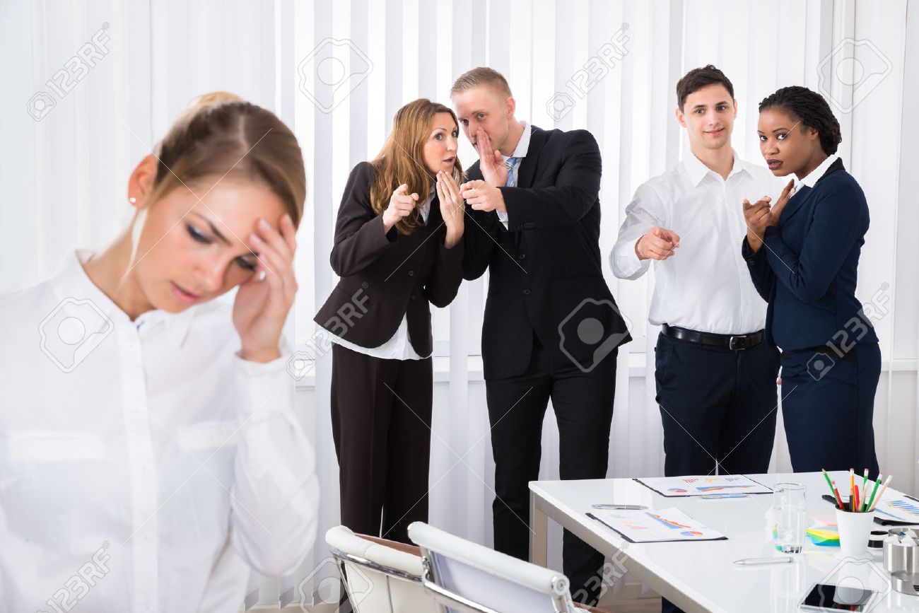 Businesspeople Gossiping Behind Stressed Female Colleague In Office - 56706586 Businesspeople Gossiping Behind Stressed Female Colleague In Office - 56706586