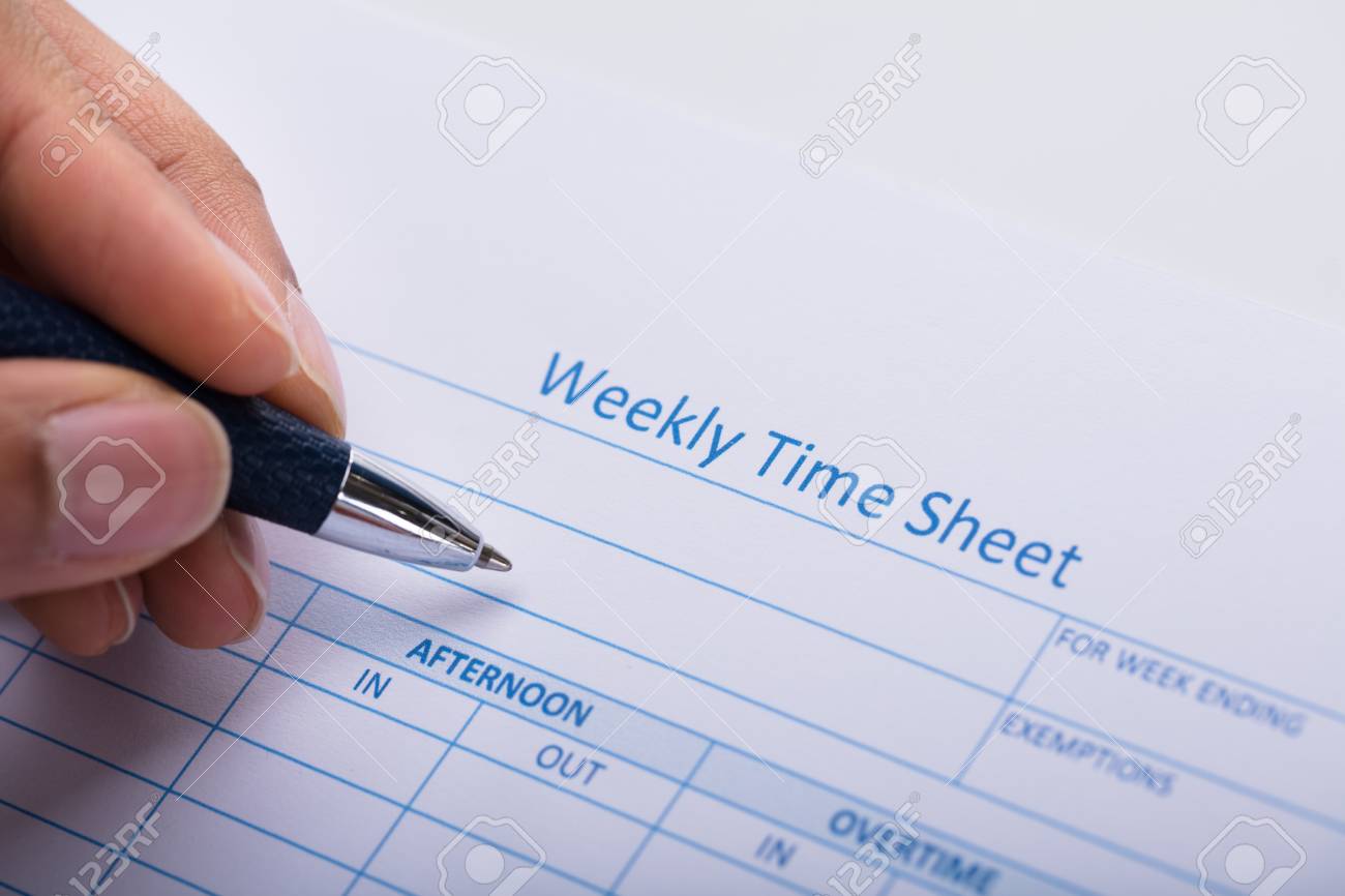 close up of a person s hand filling blank weekly time sheet with