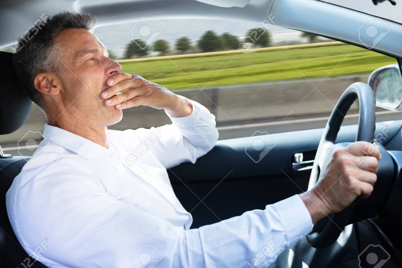106572551-side-view-of-a-mature-man-yawning-while-driving-car.jpg