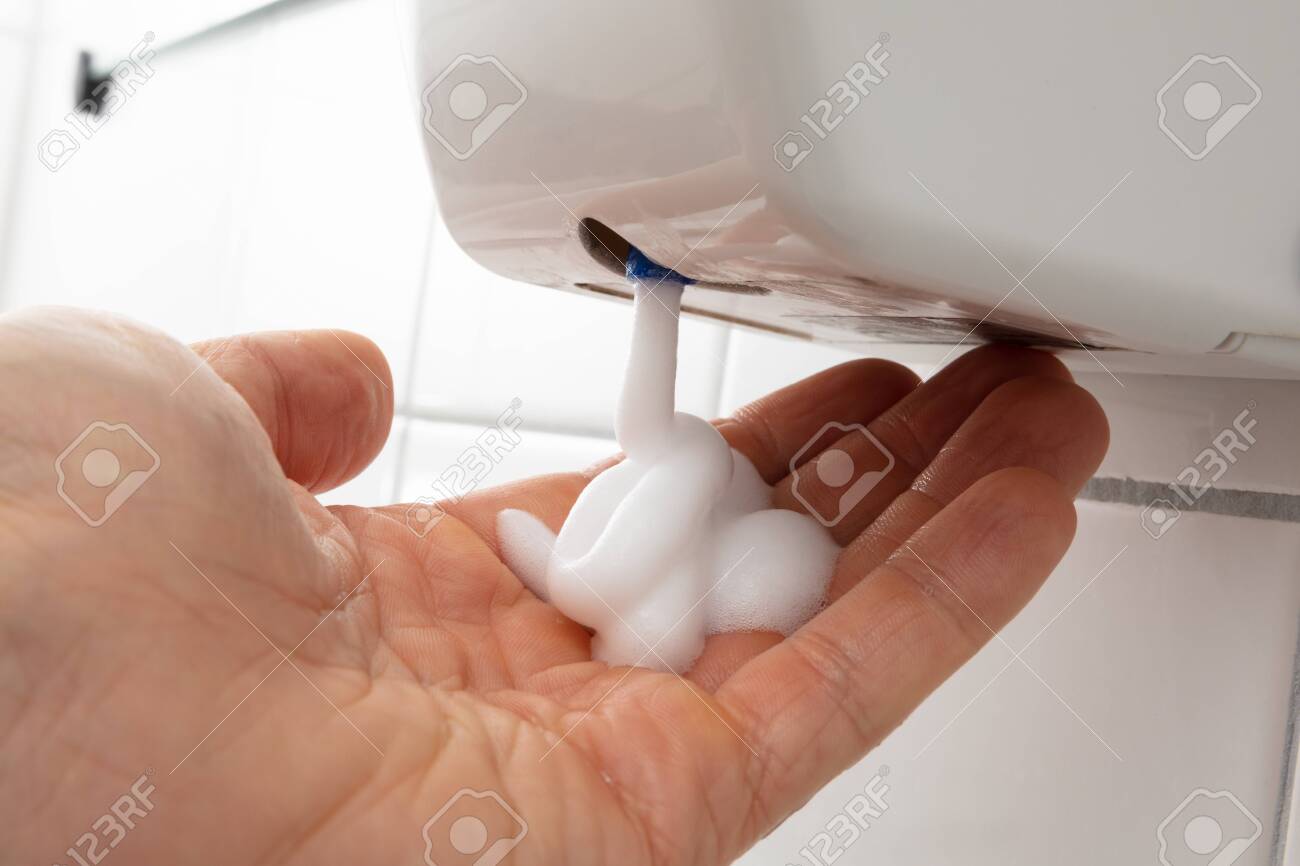 Close-up Of Person's Hand With Liquid Soap Dispenser On Tiled Wall - 121526030 Close-up Of Person's Hand With Liquid Soap Dispenser On Tiled Wall - 121526030