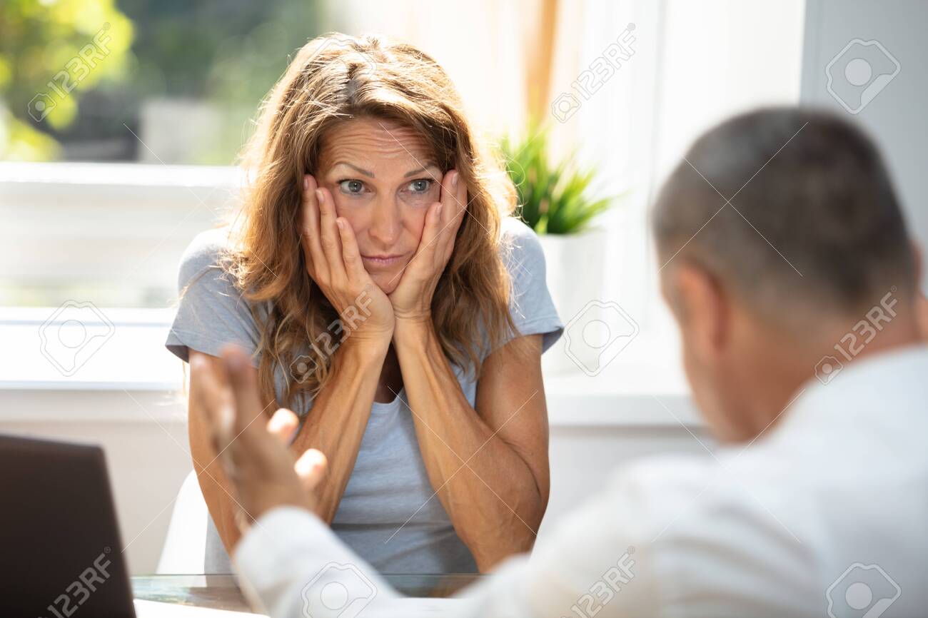 Unhappy Woman Looking At Her Colleague While Sitting In Office - 129097597 Unhappy Woman Looking At Her Colleague While Sitting In Office - 129097597