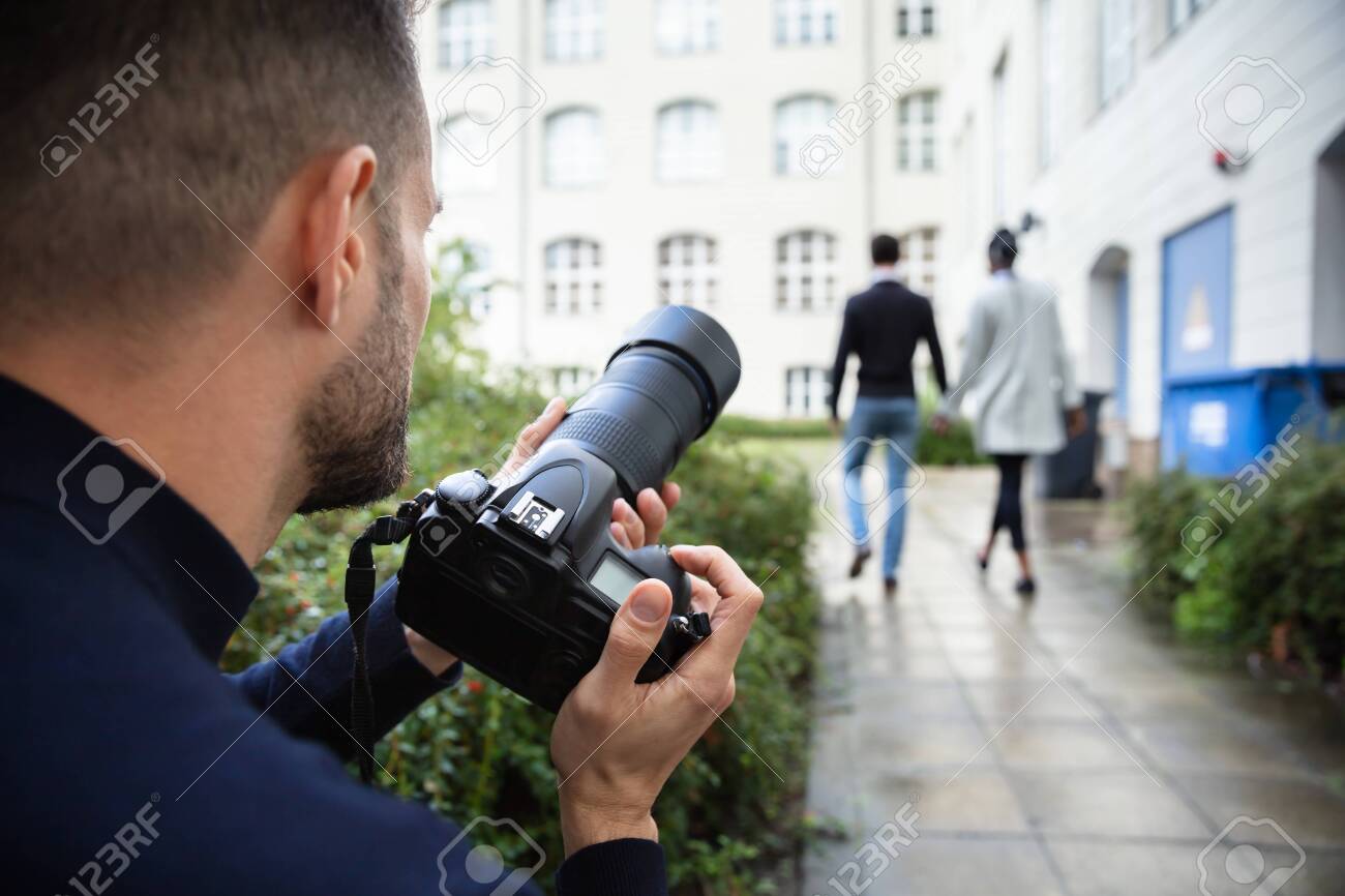 Young Man Paparazzi Photographer Capturing A Photo Suspiciously Of Couple Walking Together Using A Camera - 130976188 Young Man Paparazzi Photographer Capturing A Photo Suspiciously Of Couple Walking Together Using A Camera - 130976188
