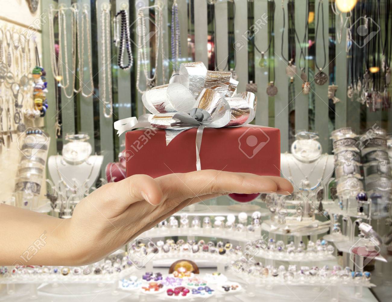 Female hand holding a gift in the background jewelry shop window - 50364504 Female hand holding a gift in the background jewelry shop window - 50364504