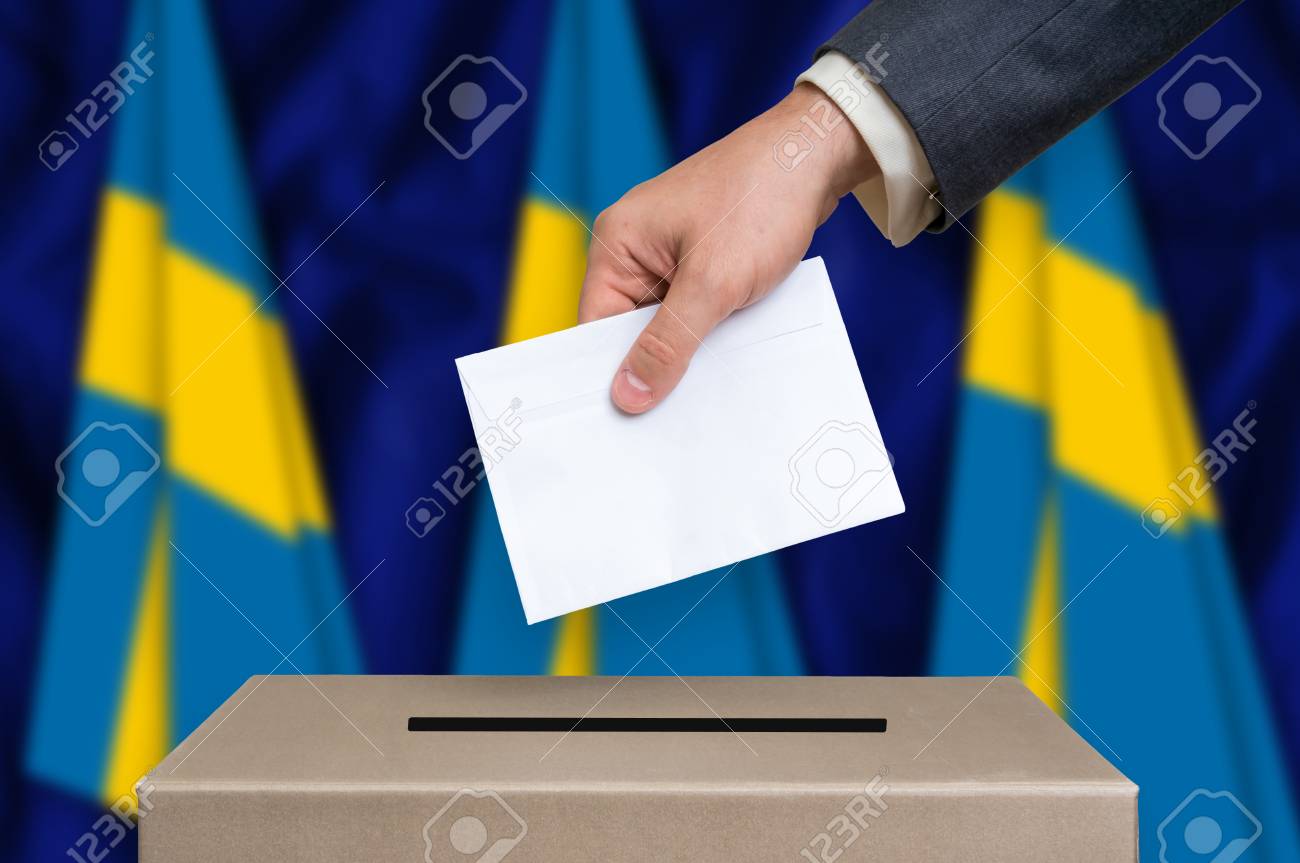 スウェーデンの選挙 投票箱に自分の一票を入れて男の手 背景にスウェーデンのフラグです の写真素材 画像素材 Image