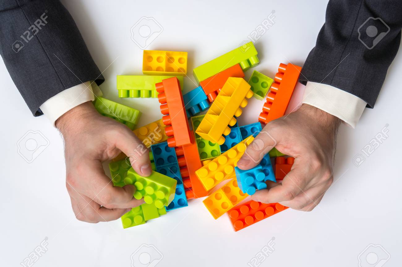 Concept of strategy and reorganization business ideas - young businessman playing with colored toy blocks - 94390966 Concept of strategy and reorganization business ideas - young businessman playing with colored toy blocks - 94390966