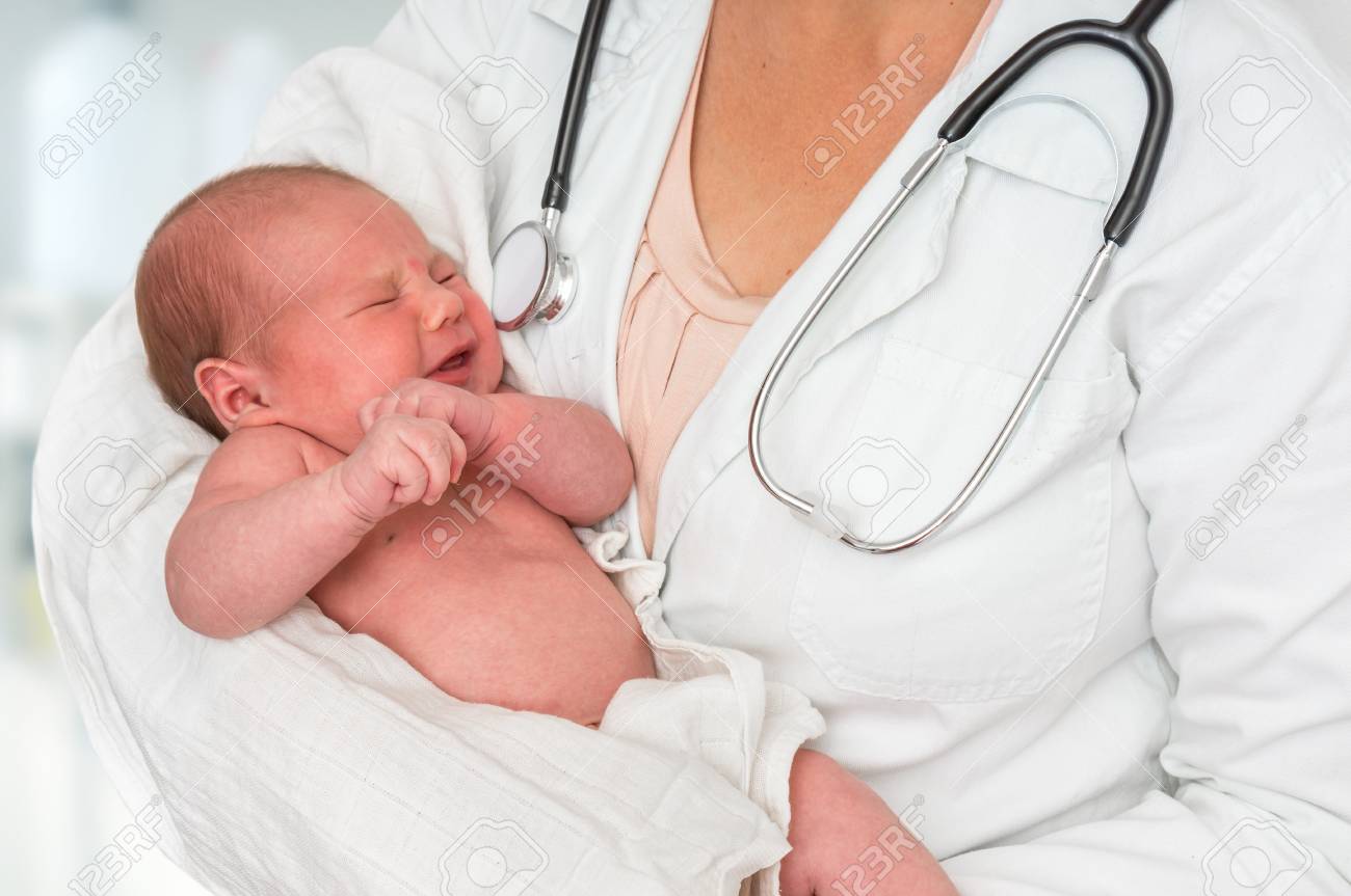 Pediatrician doctor with stethoscope is holding newborn baby in arms - 114739160 Pediatrician doctor with stethoscope is holding newborn baby in arms - 114739160