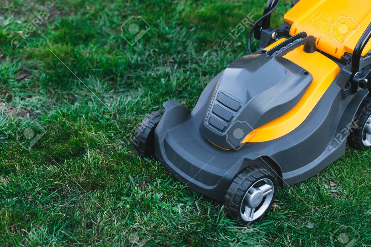 Electric lawn mower on a lawn at the garden. gardening concept - 153484665 Electric lawn mower on a lawn at the garden. gardening concept - 153484665