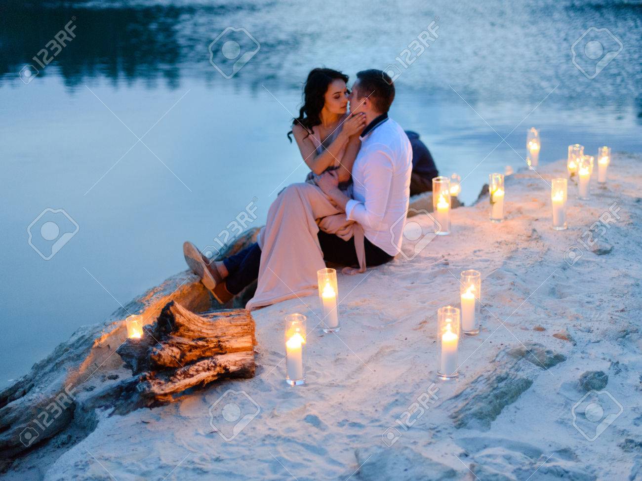 Schoner Mann Und Sinnliche Brunette Frau Am Strand Am See Von Vielen Kerzen Gegen Den Sonnenuntergang Umgeben Romantische Liebesgeschichte Lizenzfreie Fotos Bilder Und Stock Fotografie Image 58057644